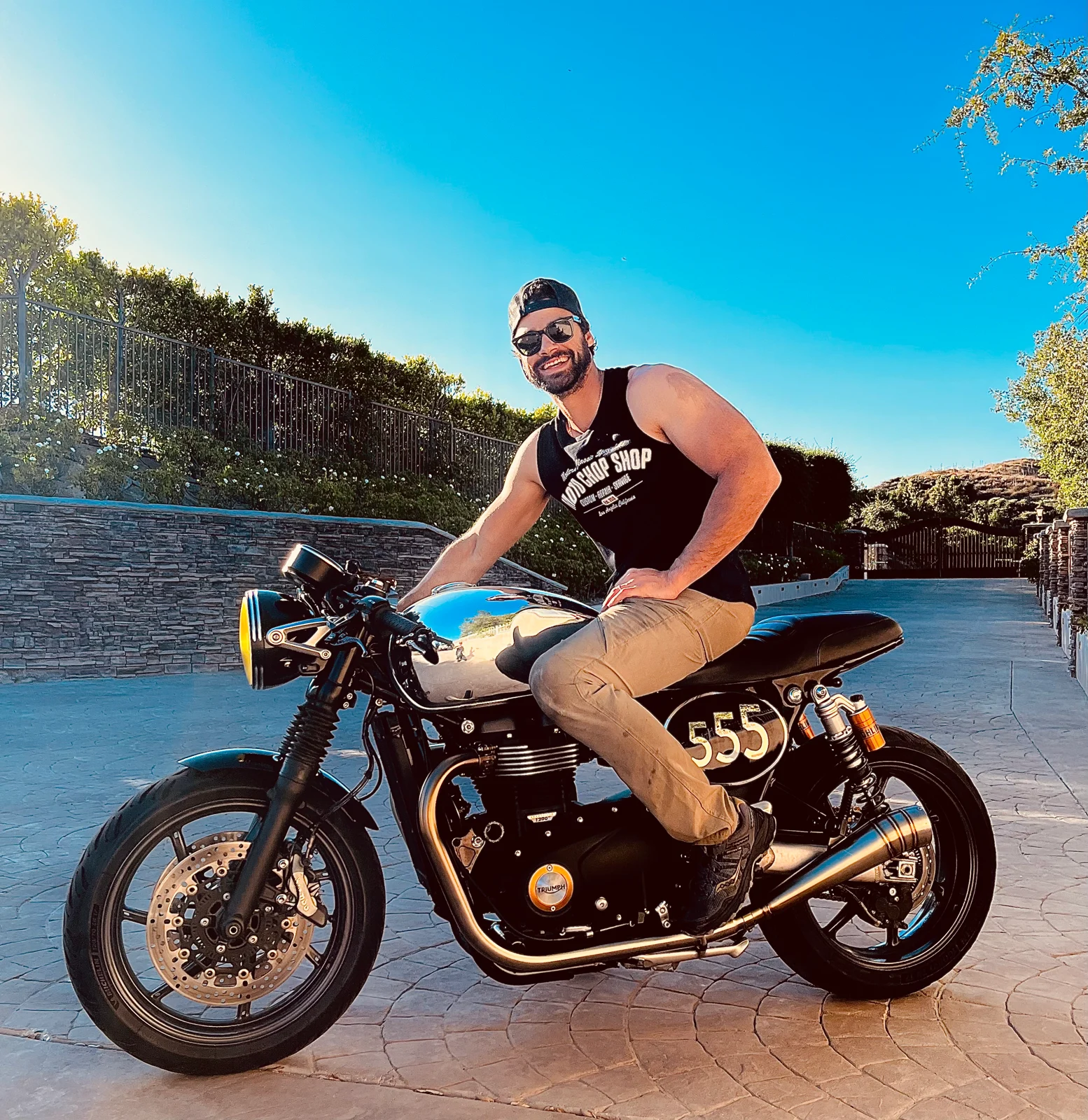 Casual & Friendly Shot (Sunglasses & Hat)
Kris Van Damme sitting on his motorcycle, wearing sunglasses and a hat, with a relaxed and friendly expression.